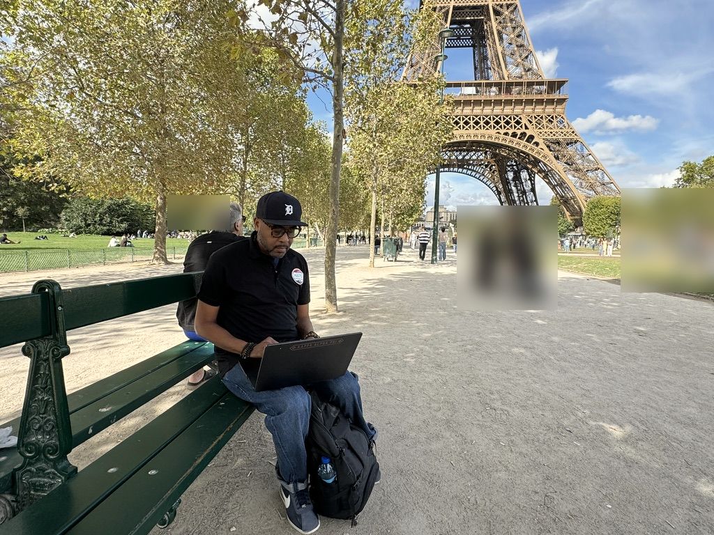 Jones Mays working on a laptop on a park bench near the Eiffel Tower