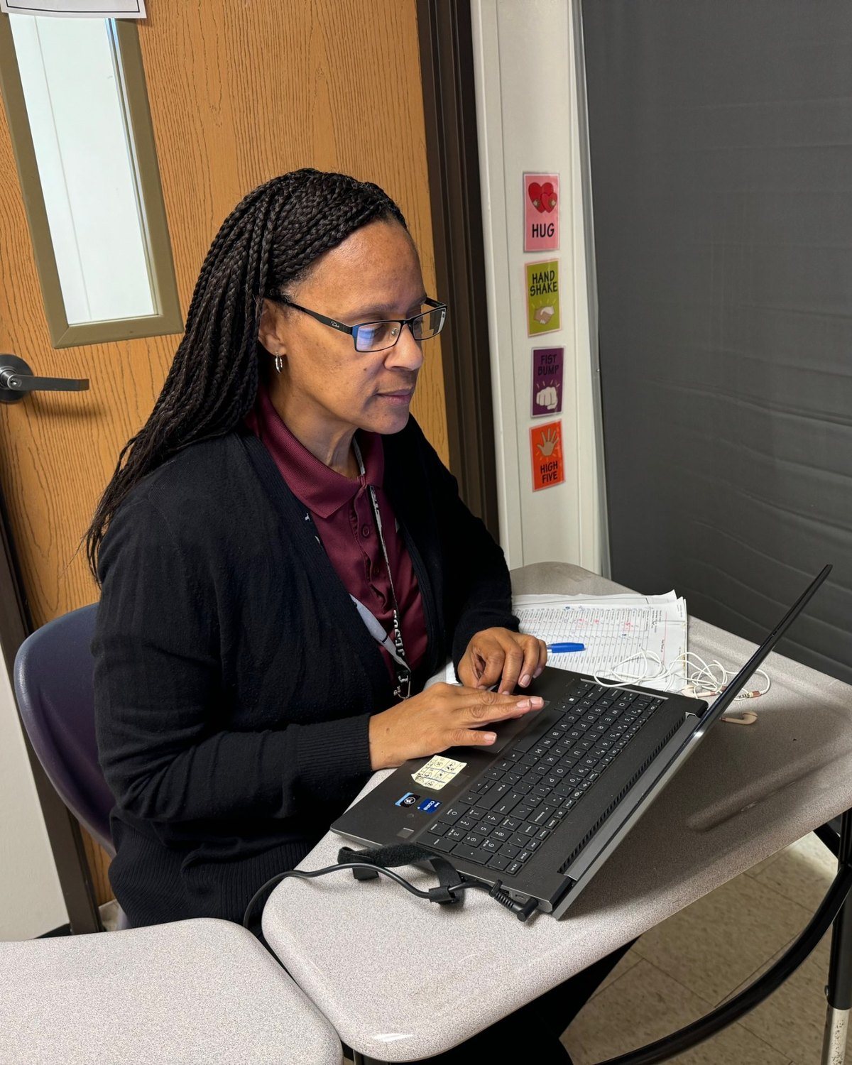 The woman in the maroon polo working on a laptop: the tall photo in the home page’s “One partner for the whole technology department” section. It reads like a real school staffer, which fits.